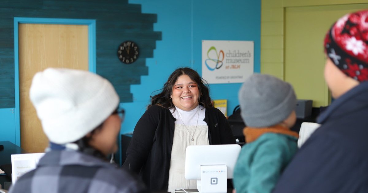 Museum staff checking in a family at the front desk of the Children's Museum at JBLM.