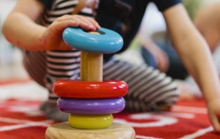 Child stacking colorful rings on top of each other.