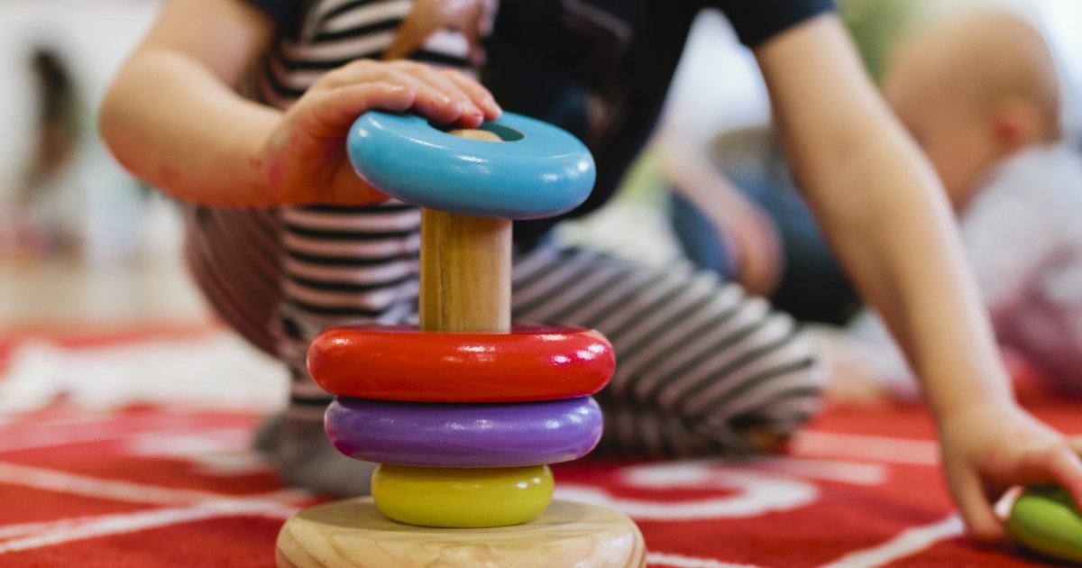 Child stacking colorful rings on top of each other.