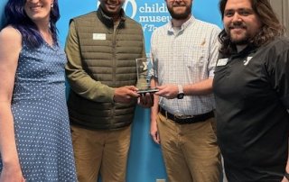 Group of four people smiling with Partner of the Year award in the middle
